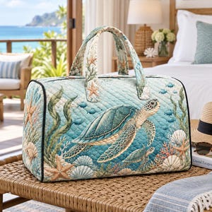 Può includere: Una borsa da viaggio trapuntata con una stampa oceanica blu e verde acqua raffigurante tartarughe marine, stelle marine, conchiglie e alghe. La borsa presenta due manici in tessuto coordinato, una base rettangolare e profili neri.