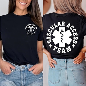 May include: Black t-shirt with white text and graphics. The front features a medical symbol and the words "Vascular Access Team" with a name below. The back displays a larger version of the same design. The shirt is worn with blue jeans.