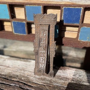 Un antiguo buzón de metal fundido pesado, altamente decorado, con fascia y llamador de puerta combinados de 17 cm de alto