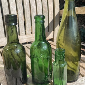 Cuatro botellas de vidrio verde antiguas y vintage.