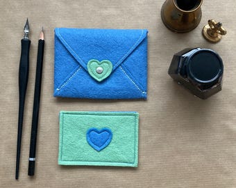 May include: Two felt envelopes with a heart design. The larger envelope is blue with a light green heart. The smaller envelope is light green with a blue heart.