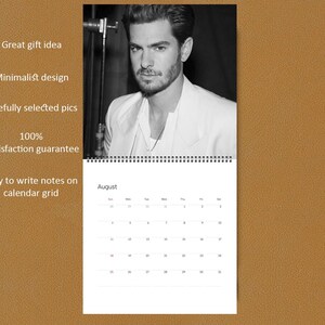 May include: A wall calendar featuring a black and white portrait of a man with a beard wearing a light-colored blazer. The calendar page displays the month of August with a grid of dates. Text on the left includes Great gift idea, Minimalist design, Carefully selected pics, 100% Satisfaction guarantee, and Easy to write notes on calendar grid.