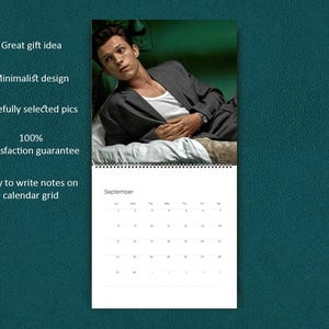 K&ouml;nnte beinhalten: Ein Wandkalender mit einem Foto einer Person mit dunklem Haar, die einen grauen Blazer &uuml;ber einem wei&szlig;en Unterhemd tr&auml;gt und auf wei&szlig;er Bettw&auml;sche liegt. Der untere Teil zeigt ein Kalendergitter f&uuml;r den Monat September mit der Aufschrift September.