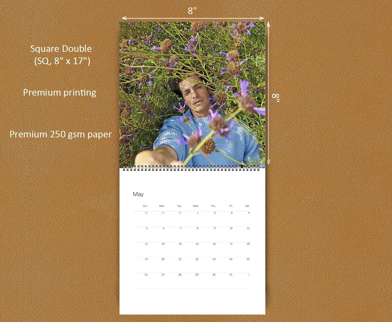 May include: A square double wall calendar measuring 8 inches by 17 inches, printed on 250 gsm paper. The top section features a photograph of a person in a blue sweater amidst purple flowers. The bottom section displays a May calendar grid.