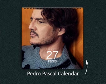 Könnte beinhalten: Ein Wandkalender mit einem Porträt von Pedro Pascal, der einen grau-schwarz gemusterten Pullover trägt. Der Text auf dem Kalender lautet TWENTY 27 PEDRO. Der Kalender ist oben spiralgebunden und enthält den Text Pedro Pascal Calendar.