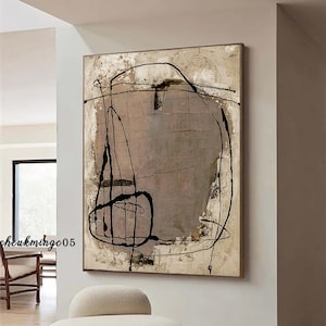 May include: Abstract painting with black lines and shapes on a beige background. The painting is hanging on a wall in a room with a white chair.