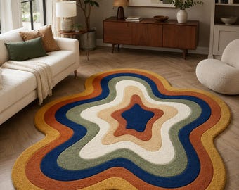 May include: An irregular, organic-shaped area rug featuring concentric, wavy bands of color. The palette includes mustard yellow, burnt orange, deep navy blue, sage green, and cream, creating a layered, topographical effect on the floor.