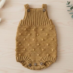 Peut inclure: Barboteuse pour bébé en crochet jaune moutarde avec fermetures boutonnées. La barboteuse présente un motif de point texturé avec des boules et des détails côtelés sur les bretelles. Une tenue confortable et élégante pour bébé.