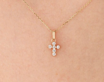 May include: A delicate gold chain necklace with a small diamond cross pendant.