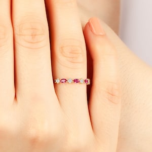 May include: A gold band ring with alternating oval-shaped rubies and round diamonds.