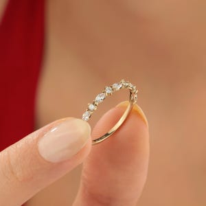 May include: A delicate gold band ring with a row of small, clear, marquise-shaped diamonds.