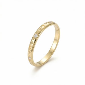 May include: A gold ring with a star pattern and small, clear gemstones. The ring has a smooth, polished finish and a delicate design. The gemstones are evenly spaced around the ring, adding a touch of sparkle.