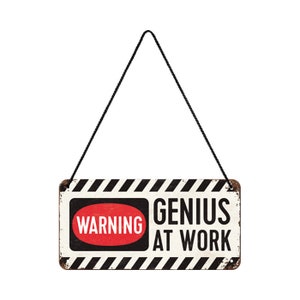 Könnte beinhalten: Ein weiß-schwarz gestreiftes Schild mit dem Text "WARNING GENIUS AT WORK" in schwarzen Buchstaben. Das Wort "WARNING" befindet sich in einem roten Oval.