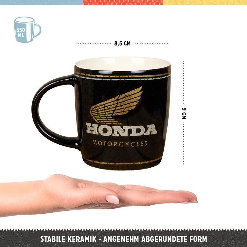 K&ouml;nnte beinhalten: Schwarze Keramik-Tasse mit dem Honda Motorcycles Logo in Gold. Die Tasse ist 9 cm hoch und 8,5 cm breit. Sie hat einen schwarzen Henkel und eine wei&szlig;e Innenseite. Fassungsverm&ouml;gen 330 ml.