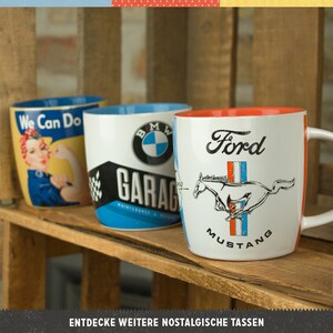 K&ouml;nnte beinhalten: Drei Keramikbecher mit Automobil- und Vintage-Themen. Ein Becher zeigt ein Rosie-the-Riveter-Design mit dem Text "We Can Do". Ein weiterer Becher zeigt das BMW-Logo und das Wort "GARAGE". Der dritte Becher hat das Ford Mustang-Logo.