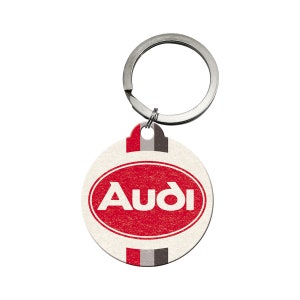 Puede incluir: Un llavero blanco y rojo con la palabra "Audi" en letras blancas sobre un óvalo rojo. El llavero tiene un anillo plateado y un fondo blanco con rayas rojas, grises y negras.