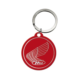 Puede incluir: Llavero de metal rojo con un logotipo de ala de Honda plateado y las letras "HM" en el centro.