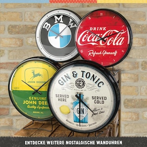 Può includere: Quattro orologi da parete rotondi con cornici nere e design diversi. Gli orologi presentano un logo BMW, un logo Coca-Cola, un logo John Deere e un logo Gin & Tonic. Gli orologi sono esposti su un supporto in metallo nero.