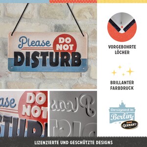 Puede incluir: Un letrero de metal con un c&iacute;rculo rojo y las palabras "No molestar" en letras negras. El letrero est&aacute; colgado de una cuerda y tiene agujeros preperforados. El letrero est&aacute; dise&ntilde;ado en Berl&iacute;n, Alemania.