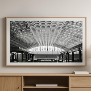 May include: Black and white photograph of a large, open space with a vaulted ceiling. The ceiling is made of a grid of metal beams and panels. The space is empty, except for a few pillars and a small amount of furniture.