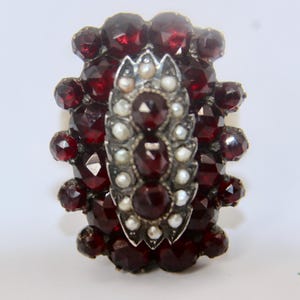 Può includere: Un broche vintage con un gruppo di pietre di granato rosso e accenti di perle incastonate in argento.
