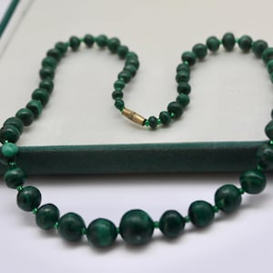 May include: A green malachite bead necklace with a gold clasp.