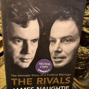 May include: A book cover with a black and white photo of two men. The title of the book is "The Rivals" and the author is "James Naughtie". The book cover also includes the text "The Intimate Story of a Political Marriage".