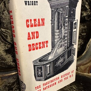 May include: A vintage book cover featuring a black and white illustration of a bathroom fixture. The title of the book is "Clean and Decent" by Lawrence Wright. The subtitle is "The Fascinating History of the Bathroom and the W.C."