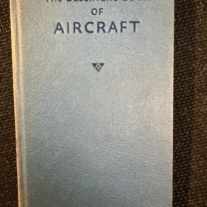 Könnte beinhalten: Ein hellblaues Buch mit dem Titel "The Observer's Book of Aircraft". Das Buch hat einen strukturierten Einband und trägt den Titel in dunkelblauer Schrift. Unter dem Titel ist ein kleines Emblem zentriert.