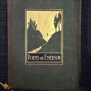 May include: A vintage book with a dark green cover and gold accents. The cover features a gold illustration of a landscape with a castle and the title "Poems of Emerson" in gold lettering. The book has a gold ribbon bookmark.
