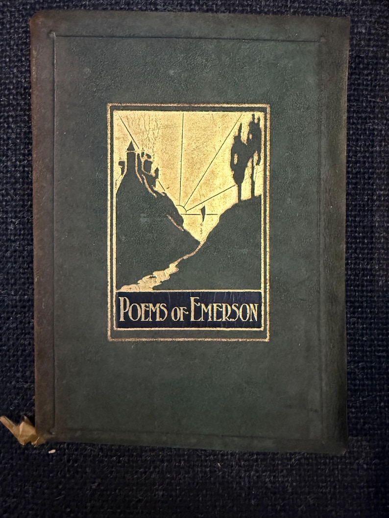 May include: A vintage book with a dark green cover and gold accents. The cover features a gold illustration of a landscape with a castle and the title "Poems of Emerson" in gold lettering. The book has a gold ribbon bookmark.