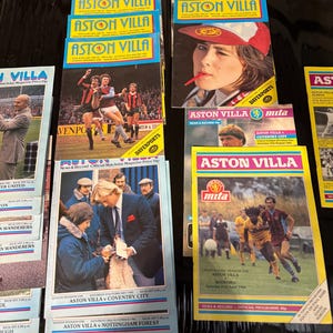 Op de afbeelding: Een verzameling vintage Aston Villa voetbalwedstrijdprogramma's. De programma's tonen kleurrijke covers met actiebeelden van spelers, teamlogo's en tekst. Sommige covers tonen portretten en tekst zoals "News & Record".