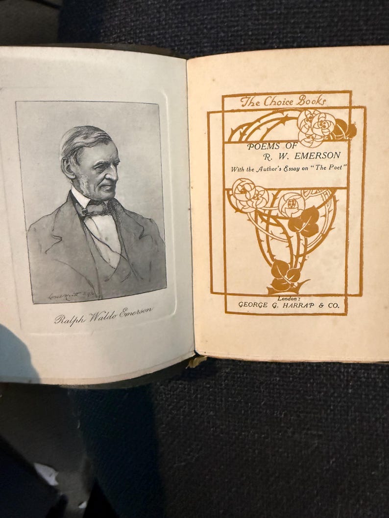May include: Open book with a black and white portrait of Ralph Waldo Emerson on the left page. The right page features the title "POEMS OF R. W. EMERSON" in brown lettering, with floral design elements and the publisher's name.
