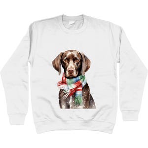 Op de afbeelding: Witte sweatshirt met een aquarel illustratie van een bruine hond met een kleurrijke sjaal. De hond heeft bruine oren en een bruine neus. De sjaal heeft rode, groene, blauwe en witte strepen. Het ontwerp staat tegen een witte achtergrond.