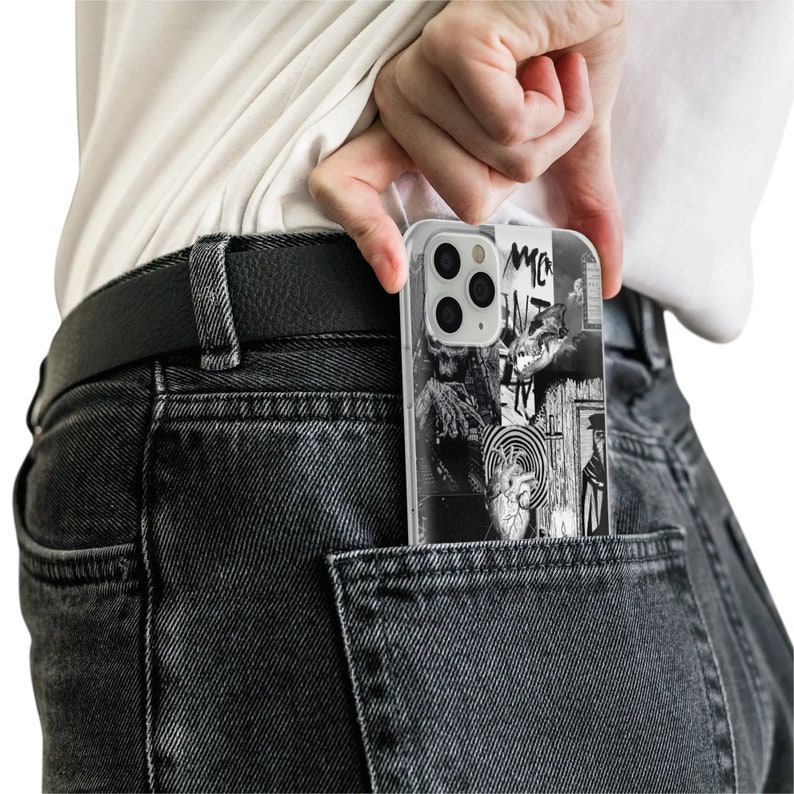 May include: A black and white phone case with a graphic design featuring a heart, a target, and other abstract shapes. The case is in a back pocket of a pair of dark gray jeans.