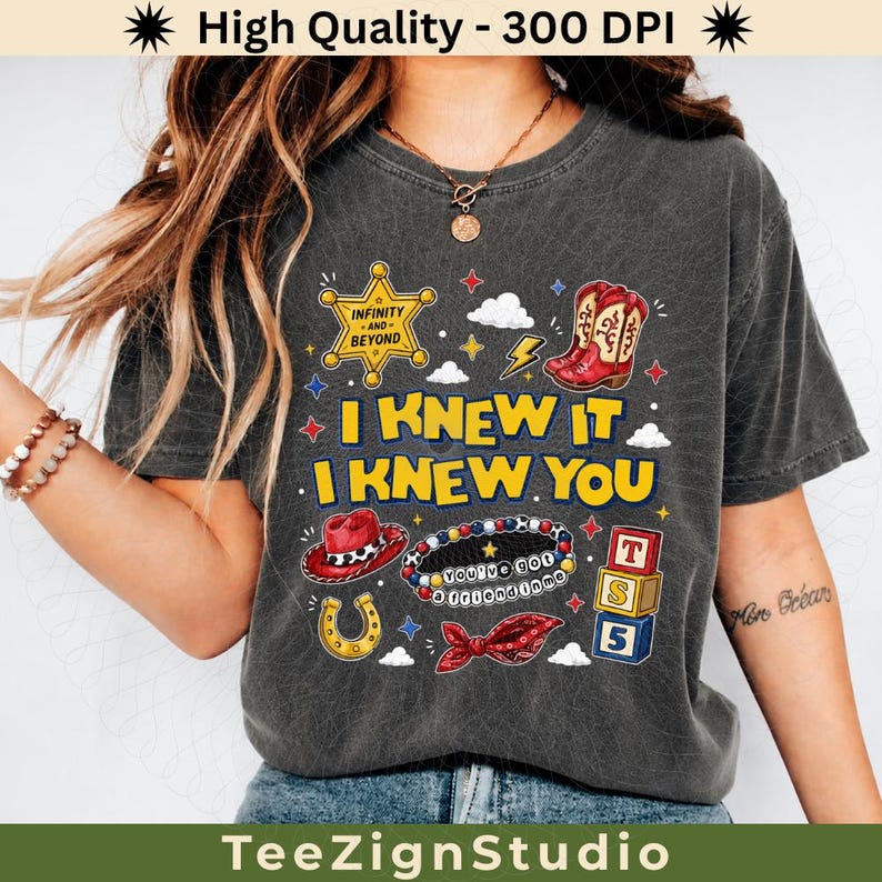 Puede incluir: Una camiseta gris carb&oacute;n de manga corta con un estampado gr&aacute;fico que incluye el texto I KNEW IT I KNEW YOU, una estrella de sheriff, botas vaqueras rojas, un sombrero rojo, una pulsera de cuentas, una herradura y tres bloques de juguete.