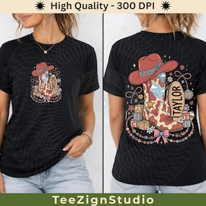May include: A black t-shirt featuring a graphic print of a cowboy boot, a cowboy hat, alphabet blocks, and a disco ball. The design includes the name TAYLOR, a pink bow, and floral accents. The same graphic appears in a smaller size on the front.