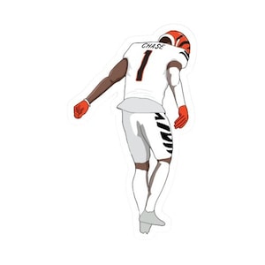 May include: A white football jersey with the number "1" and the name "CHASE" on the back. The jersey is worn by a player with black skin, and the player is in a celebratory pose, with one arm raised and the other arm bent at the elbow. The player is wearing orange and black gloves.