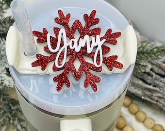 May include: A white personalised mug with a red glitter snowflake on the lid. The snowflake has the name "Jany" written on it in white.