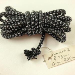 Könnte beinhalten: Schwarzes und silbernes Band mit einem Etikett mit der Aufschrift "Kumihimo 2 Ø 4,5mm Länge: 2,65m"