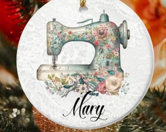 May include: A white ceramic ornament with a floral patterned sewing machine and the name "Mary" written in black cursive.