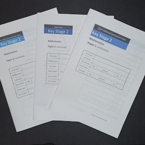 Op de afbeelding: Drie Key Stage 2 wiskundetoetsen voor 2024. De toetsen zijn getiteld "Wiskunde Papier 1: rekenen", "Wiskunde Papier 2: redeneren" en "Wiskunde Papier 3: redeneren".