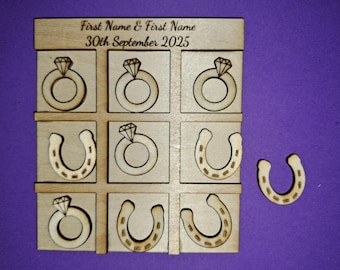 May include: Wooden tic-tac-toe game featuring ring and horseshoe symbols. The top of the board has the text "First Name & First Name 30th September 2025". A single horseshoe game piece is separate from the board.