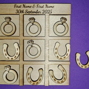 Peut inclure: Un plateau de jeu en bois avec une grille de tic-tac-toe. Les pièces du jeu sont des anneaux avec des diamants et des fers à cheval. Le plateau est gravé avec le texte "First Name & First Name 30th September 2025".