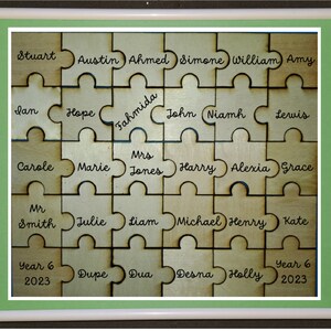 May include: A wooden puzzle featuring the names of pupils and teachers, including "Year 6 2023" at the bottom. The puzzle pieces are arranged in a grid pattern.