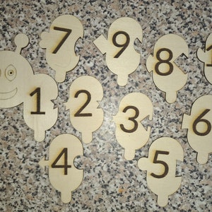 May include: Wooden puzzle pieces shaped like a caterpillar with numbers 1 through 10 on each piece. The caterpillar has a smiling face with two eyes.