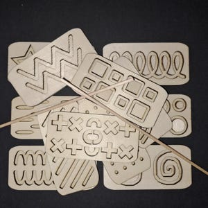 May include: A set of wooden stencils featuring a variety of geometric and abstract designs, such as zigzags, squares, circles, spirals, and crosses. The stencils are stacked on top of each other and are made from light brown wood.
