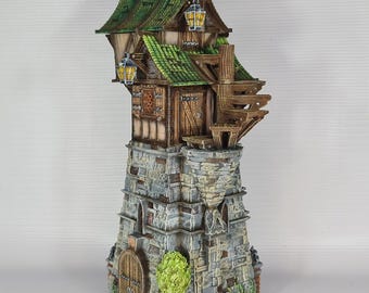 May include: A 3D printed miniature of a stone tower with a wooden house on top. The house has a green roof and windows with lanterns. The tower has a door and a small tree in front.