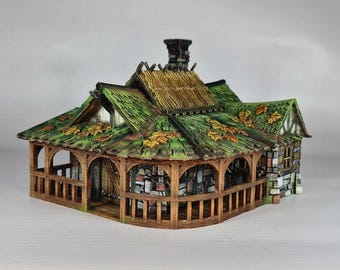 May include: A miniature wooden house with a thatched roof and a green leafy roof. The house has a porch with wooden railings and a stone foundation.