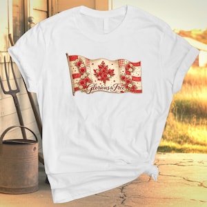 May include: White t-shirt with a floral Canadian flag design. The flag features red flowers and the text "Glorious & Free". The design is printed on a white t-shirt, suitable for casual wear.